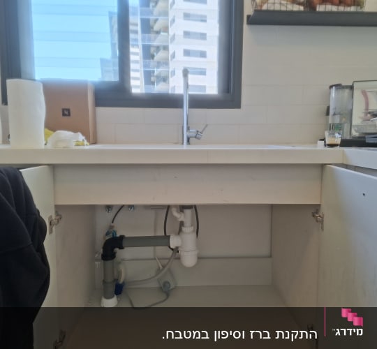 כיור מטבח עם צנרת גלויה מתחת